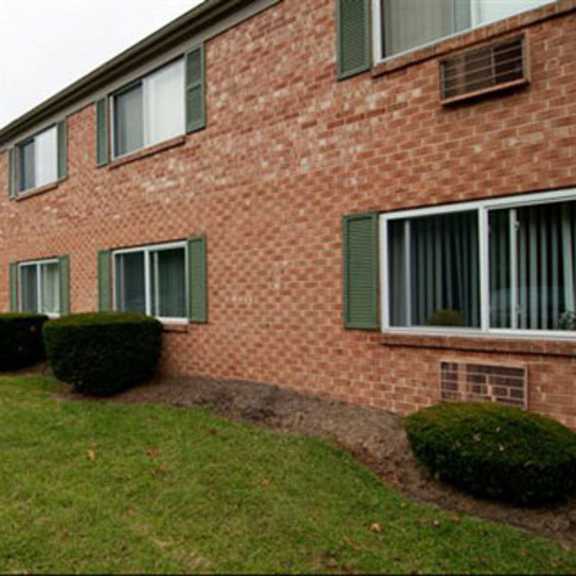 the side of a brick building with grass and bushes