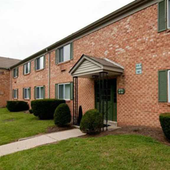the front of a brick building with a sidewalk and grass