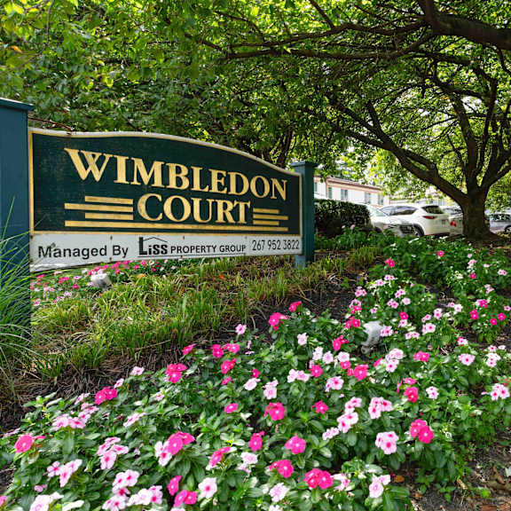 a sign that says wimbledon court in front of a tree.