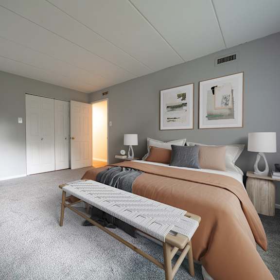a bedroom with a bed, chair, and two lamps.