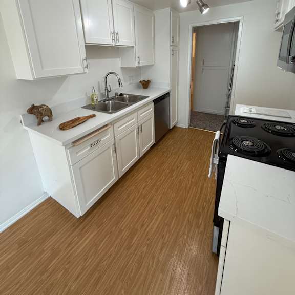 Thumbnail 1 of 6 A kitchen with white cabinets and a black stove top oven.