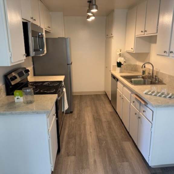 Thumbnail 4 of 4 A kitchen with white cabinets and a wooden floor.