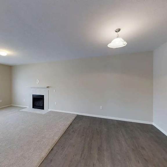 an empty living room with a fireplace and a window