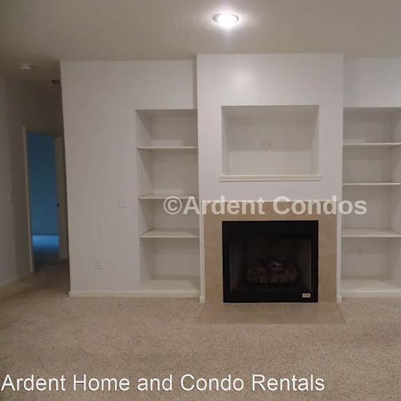 an empty living room with a fireplace and white shelves