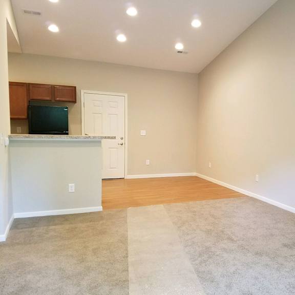 an empty living room and kitchen with a hard wood floor
