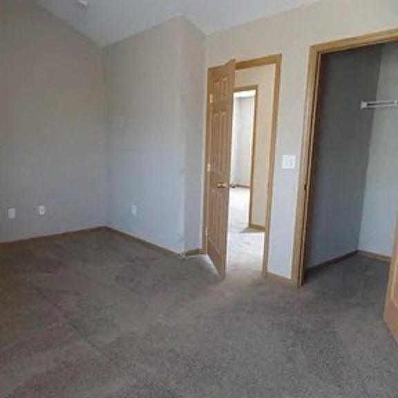 an empty living room with a door to a hallway and a door into a bedroom