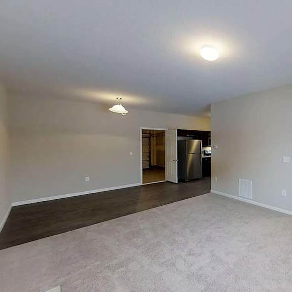 an empty living room and kitchen with a large window