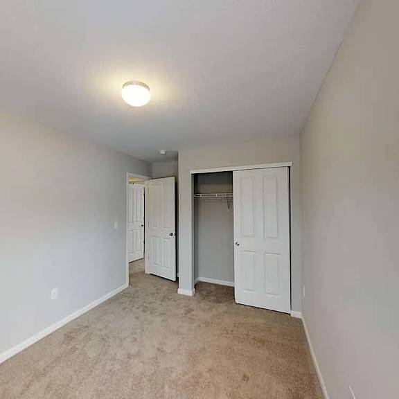 a living room with white walls and a door to a closet