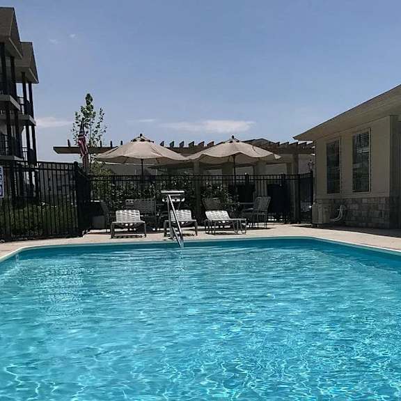 a swimming pool with chairs and umbrellas next to a house