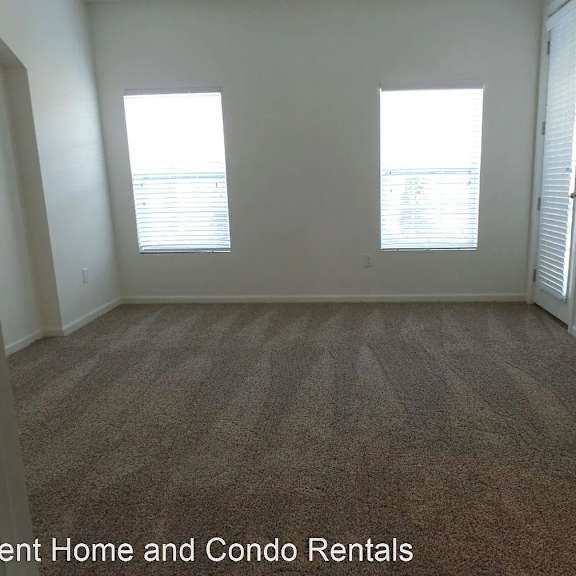 an empty living room with carpet and two windows