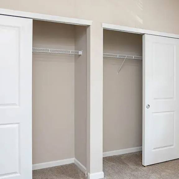 an empty closet with two doors and a window