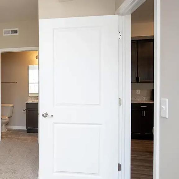 an empty room with a white door and a bathroom