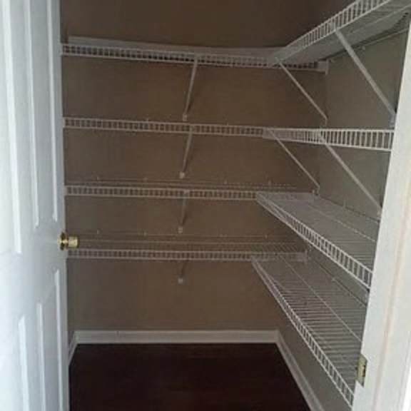 an empty closet with white shelves and a door