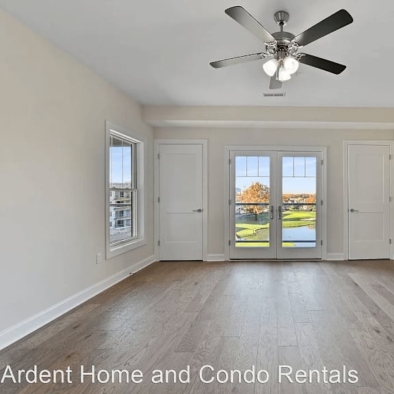 an empty living room with a ceiling fan and a window