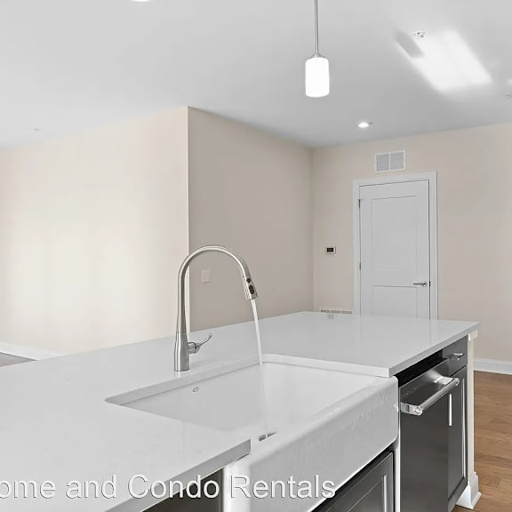 a white kitchen with a large sink and white counter tops