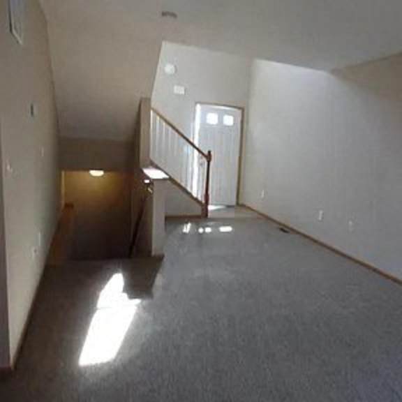 an empty living room with a staircase and a white wall