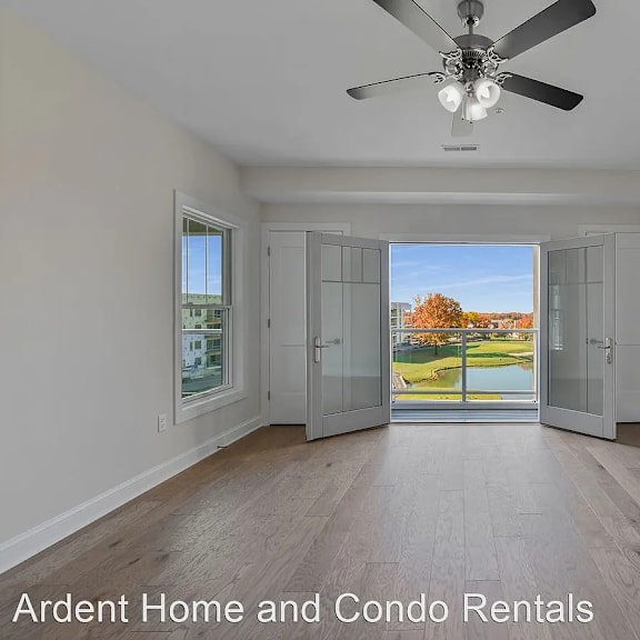 an empty living room with a balcony and a ceiling fan