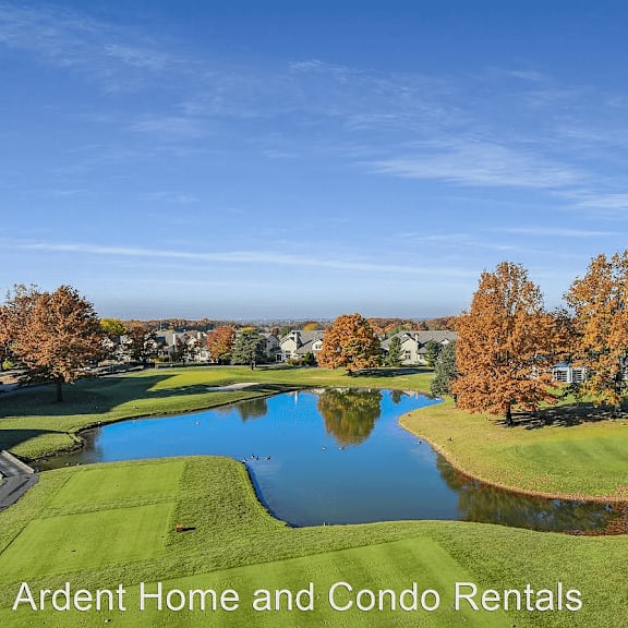 an aerial view of a golf course with a pond