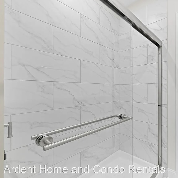 a glass shower door in a white tiled bathroom