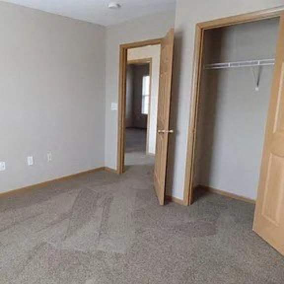 an empty room with a closet and a door to a hallway