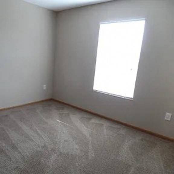 an empty room with a window and a carpet floor