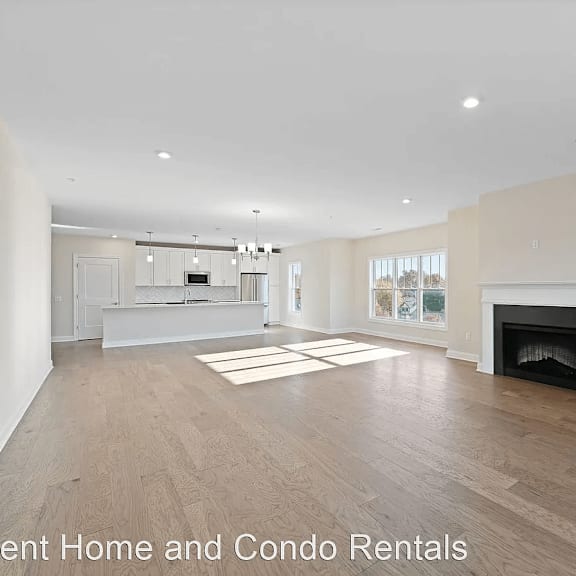 an empty living room with a fireplace and wooden floors
