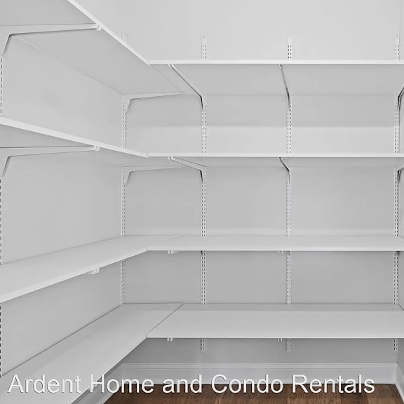 a walk in closet with white shelving and white walls