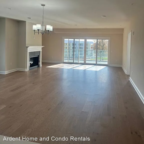 an empty living room with a fireplace and sliding glass doors