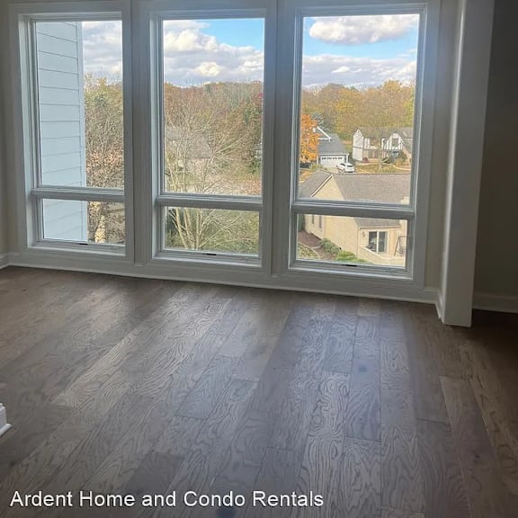 a living room with three windows and a ceiling fan