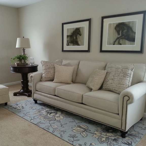 a living room with a couch, chair, and two framed pictures on the wall.