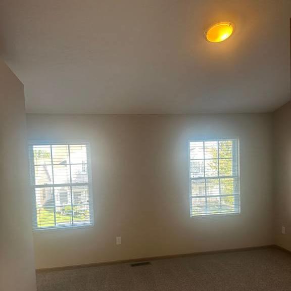 an empty room with three windows and a light on the ceiling