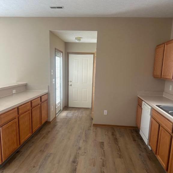 an empty kitchen with wooden floors and a white door
