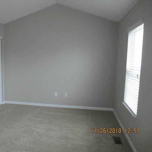 a room with a carpet floor, a door, and a window.