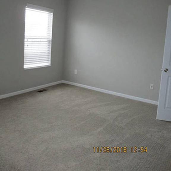 a room with a window and carpeted floor.