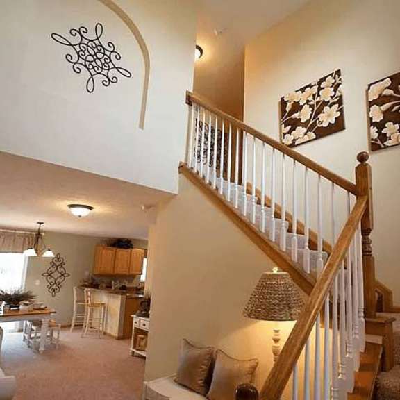 a living room with a staircase and a dining area.