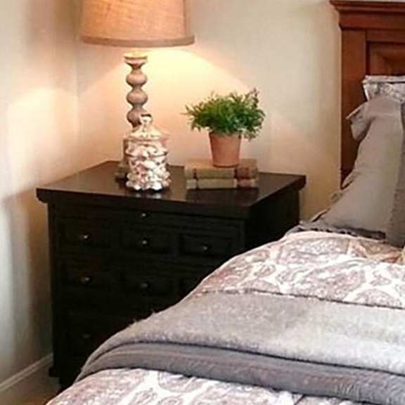 a bed with a grey comforter and a wooden headboard.