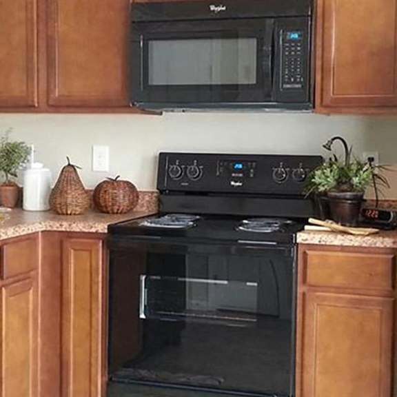 a black refrigerator sits in a kitchen with wooden cabinets.