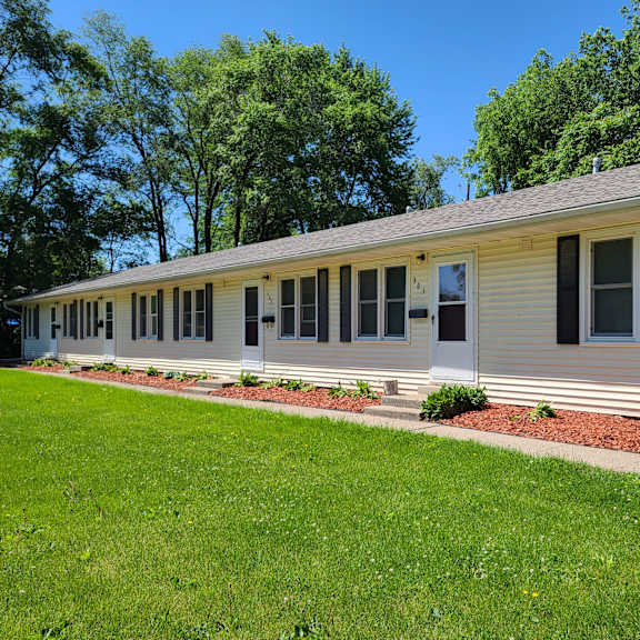 a white mobile home with a lawn and a sidewalk in front of it