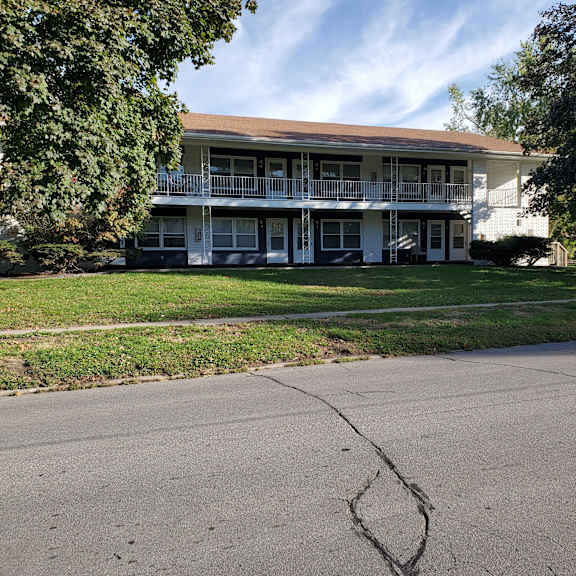 an apartment building with a cracked sidewalk in front of it