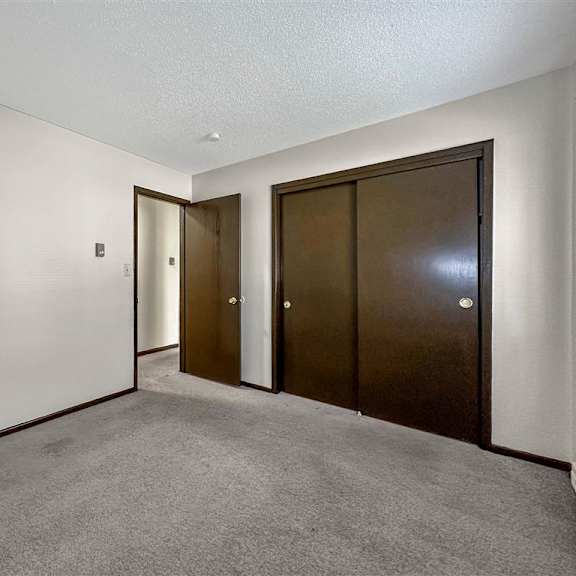 an empty room with two doors and a door to a hallway
