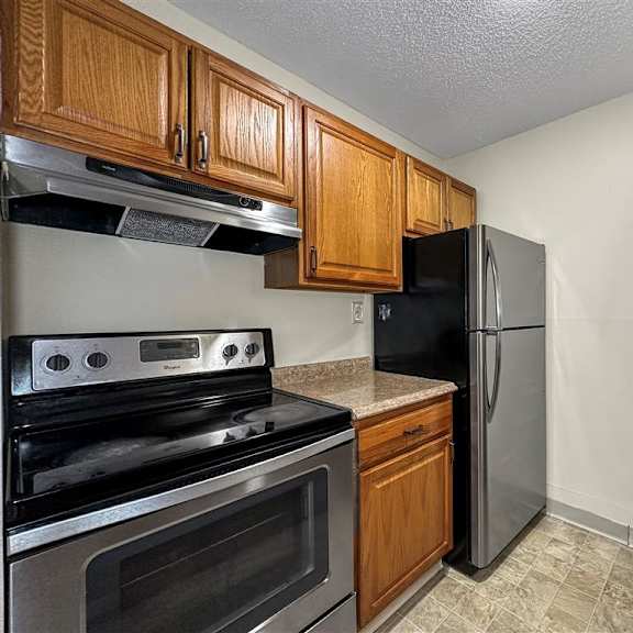 a kitchen with a stove, oven, refrigerator, and sink.