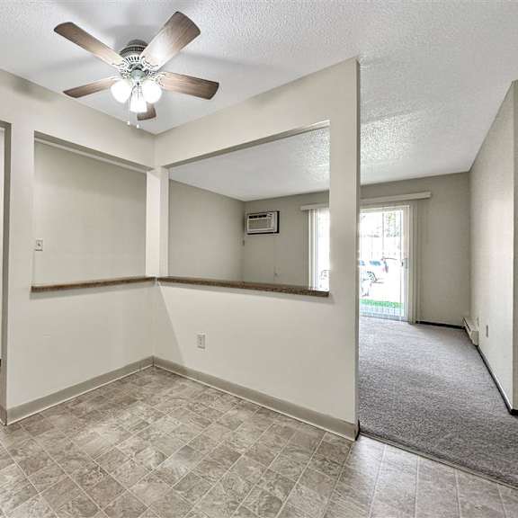 an empty living room with a ceiling fan and a mirror