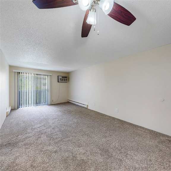 an empty living room with a ceiling fan and a window