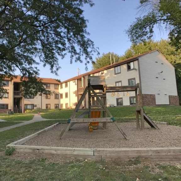 a swing set in a park in front of an apartment building