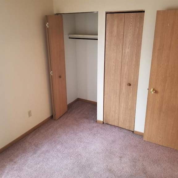 a bedroom with three doors and a carpeted floor