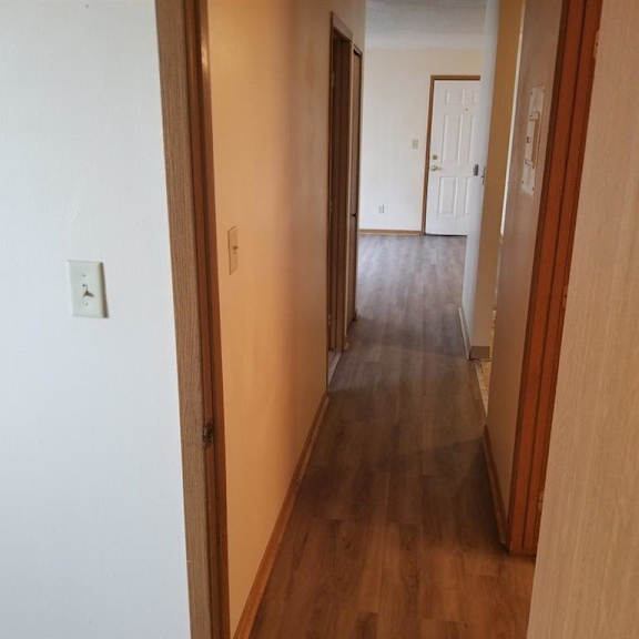a hallway with wood floors and a door to a bedroom