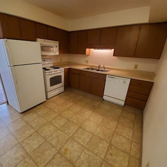 an empty kitchen with a refrigerator and a sink