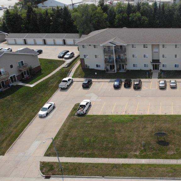 an aerial view of an apartment building and parking lot with cars