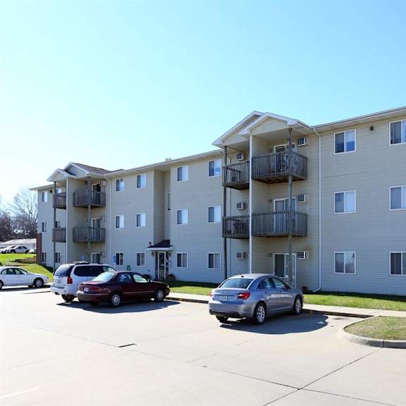 an image of an apartment building with cars parked in front