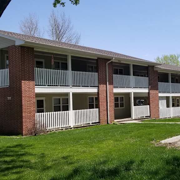 the exterior of an apartment building with a car parked outside